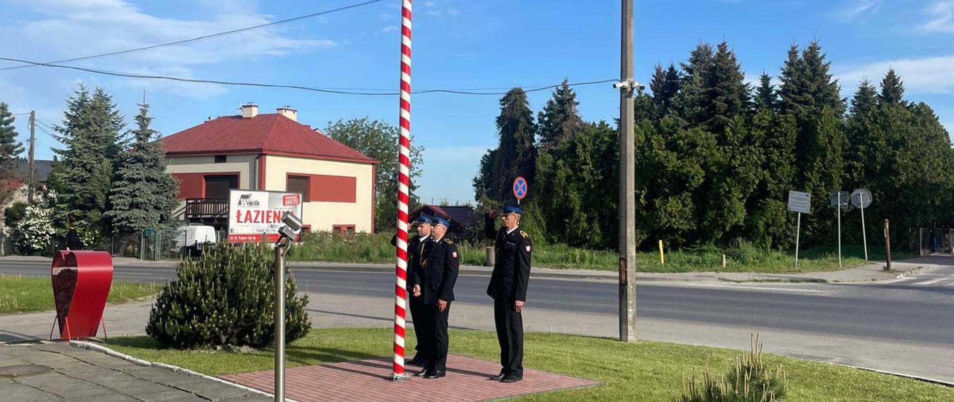 trzech strażaków wiesza flagę Polski na maszt