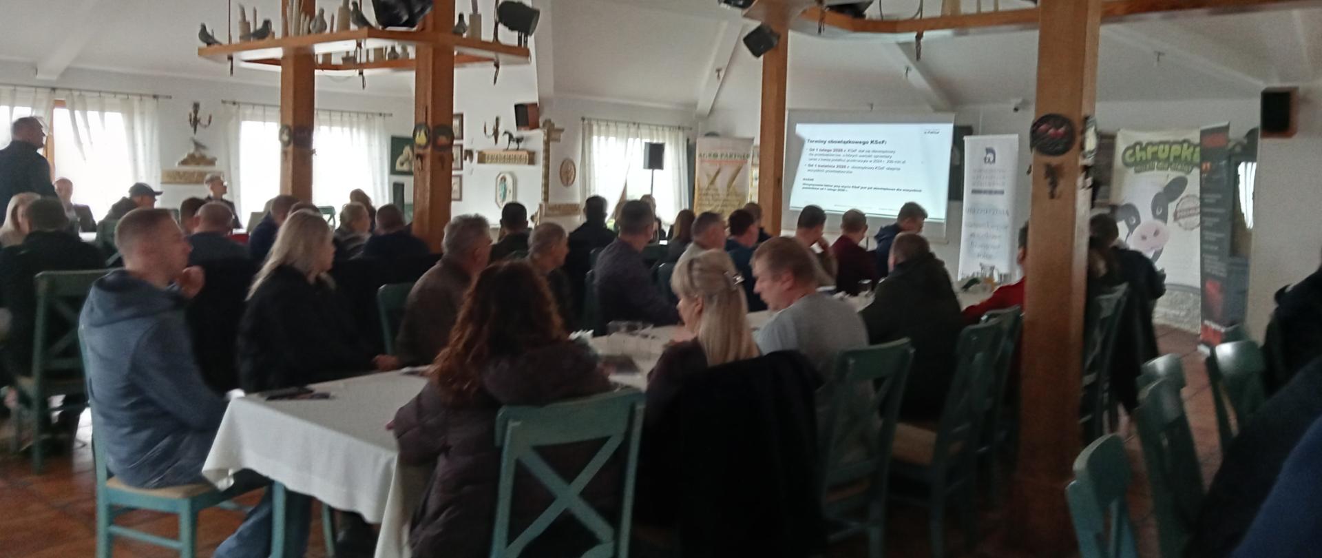 Duża grupa ludzi siedzi przy stołach w restauracji podczas konferencji