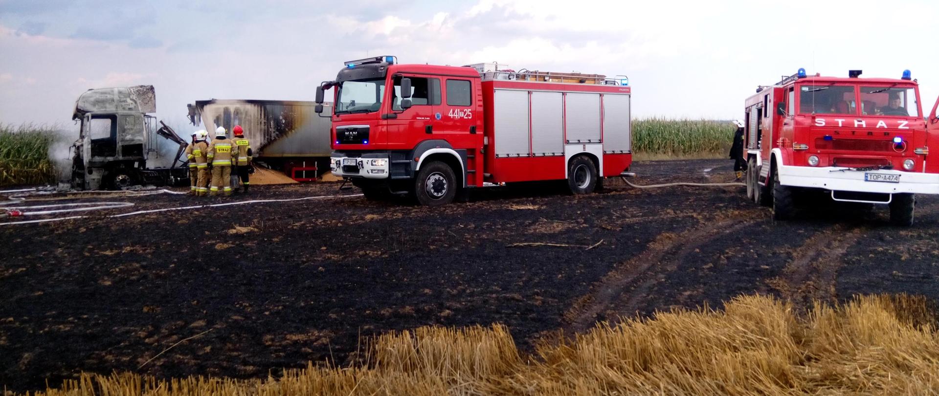 W oddali ciągnik siodłowy ze spaloną kabiną, na pierwszym planie wóz bojowy straży pożarnej