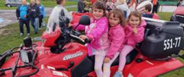 Trzy dziewczynki siedzące na specjalnym pojeździe terenowym typu quad.