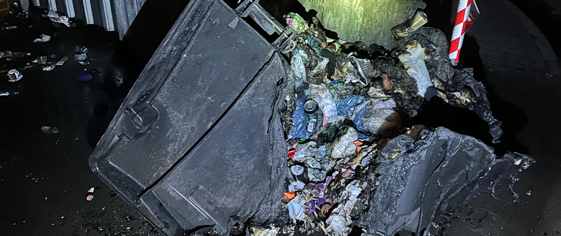 Zdjęcie przedstawia zniszczony przez ogień kontener śmietnikowy wraz z zawartością na zapleczu technicznym dyskontu.