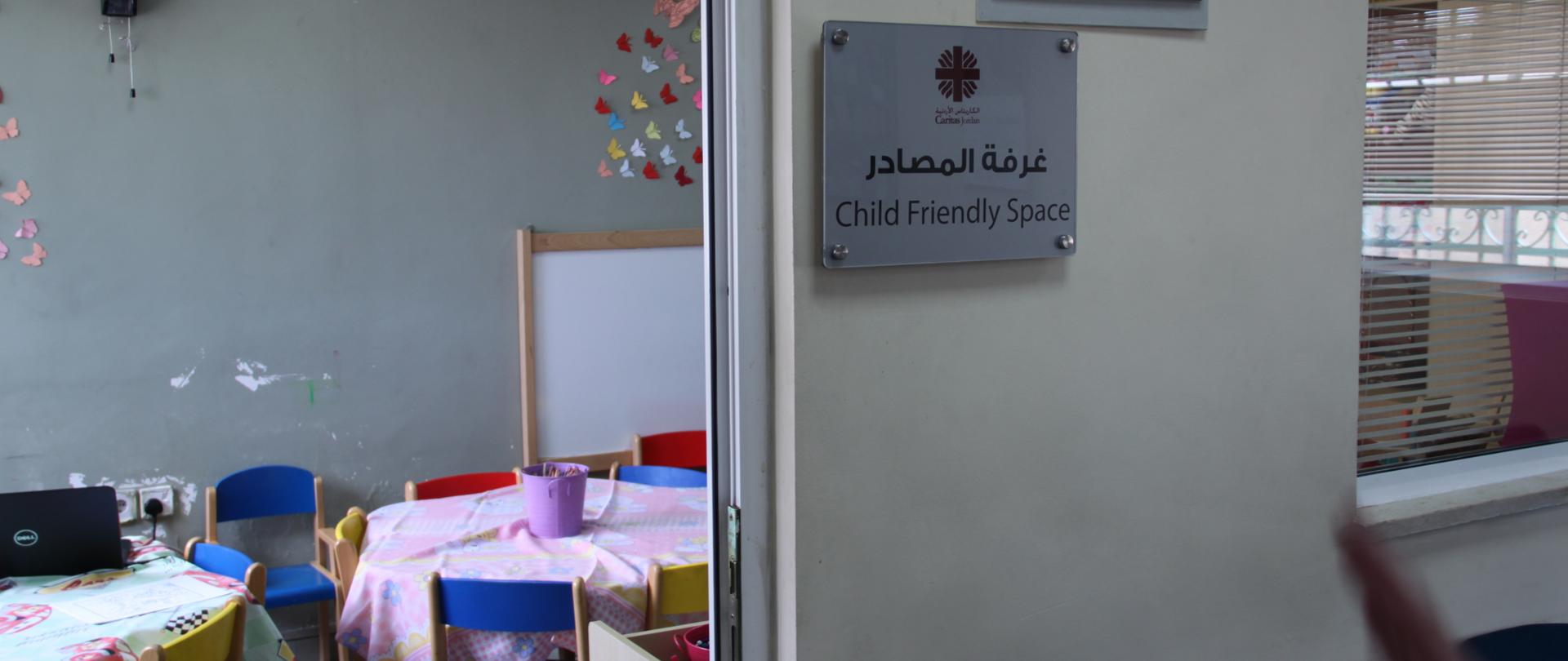 tabliczka informacyjna o sali zabaw dla dzieci z informacją, iż jest to miejsce prowadzone przez Caritas Jordania
