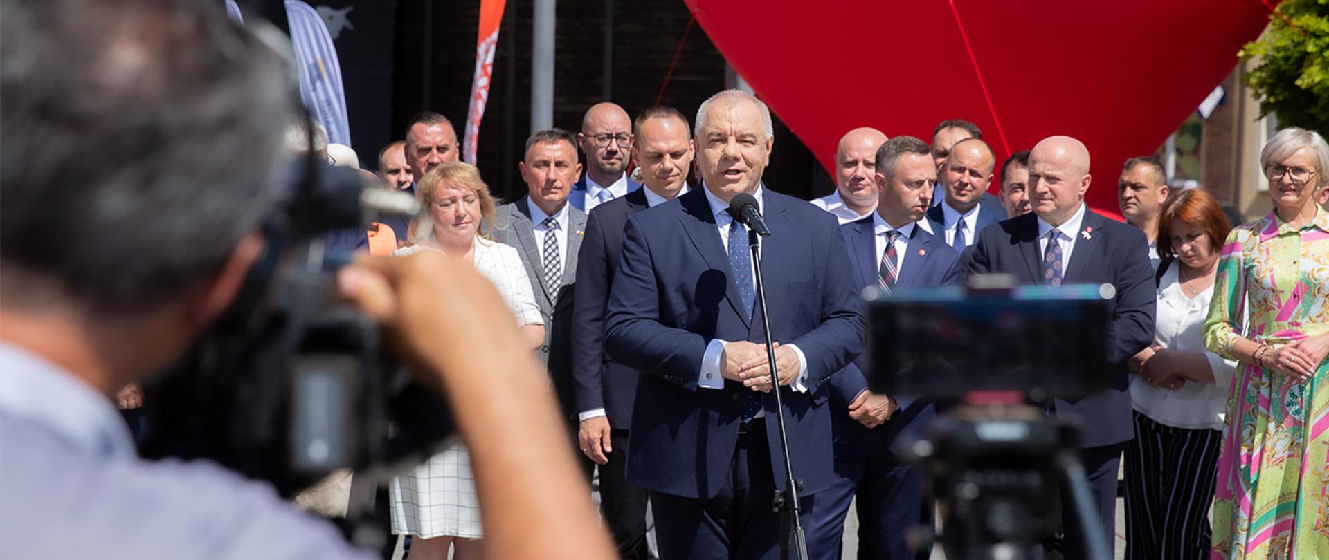 Wicepremier Jacek Sasin stoi za mikrofonem. W tle uczestnicy spotkania.