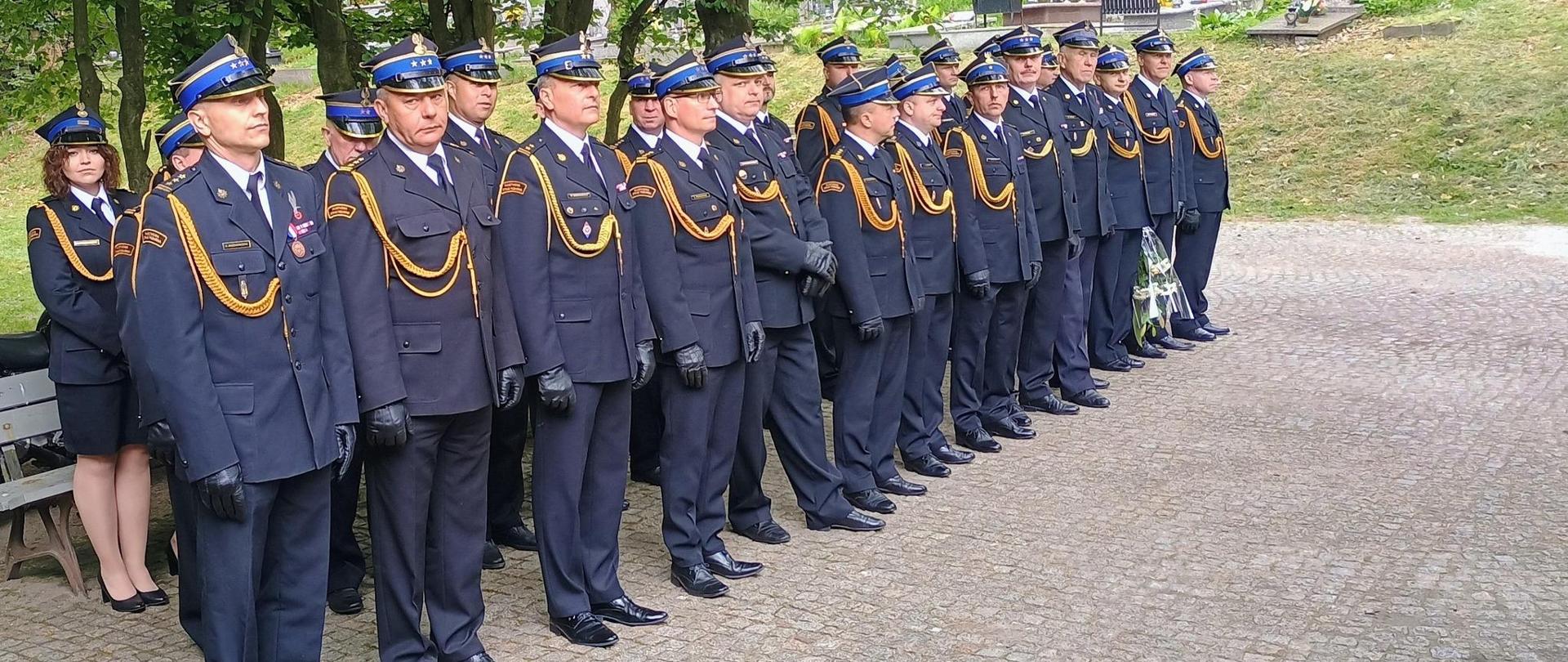 Uroczystość pogrzebowa byłego Komendanta Wojewódzkiego st. bryg. w st. spoczynku Józefa Modrasa. Strażacy w mundurach wyjściowych stoją na cmentarzu