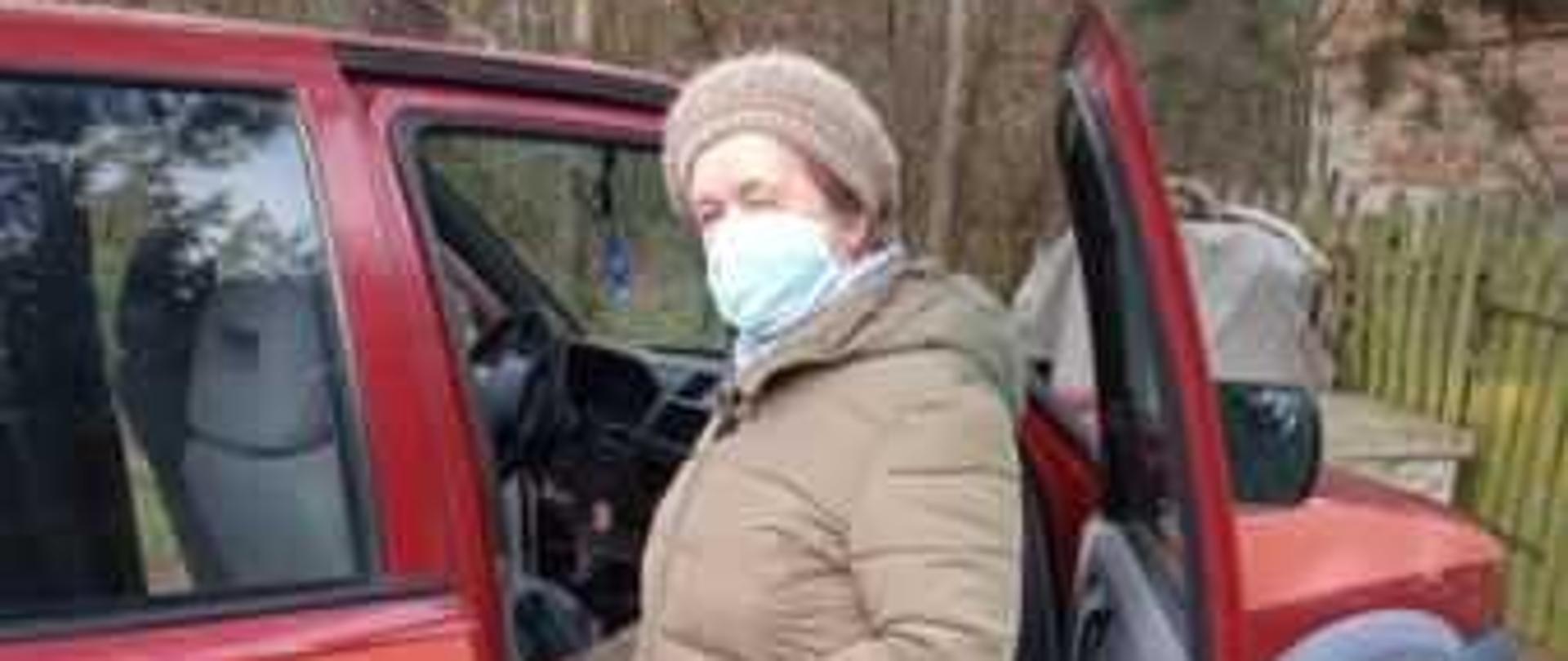 kobieta w podeszłym wieku wsiada do samochodu OSP Bobrowniki w celu udania si e na szczepienie Covid