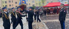 Zdjęcie przedstawia moment przekazania sztandaru dla pocztu sztandarowego przez Komendanta Powiatowego Państwowej Straży Pożarnej w Lwówku Śląskim starszego brygadiera Mariusza Mróz. 