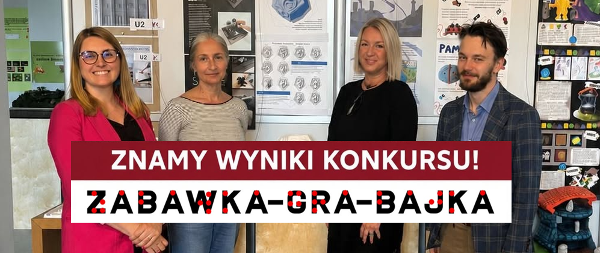 Na zdjęciu czterej członkowie Jury konkursowego - trzy kobiety i jeden mężczyzna - na tle pracy zaprezentowanych w postaci plansz i modeli. Na pierwszym planie napis: znamy wyniki konkursu "Zabawka gra bajka"