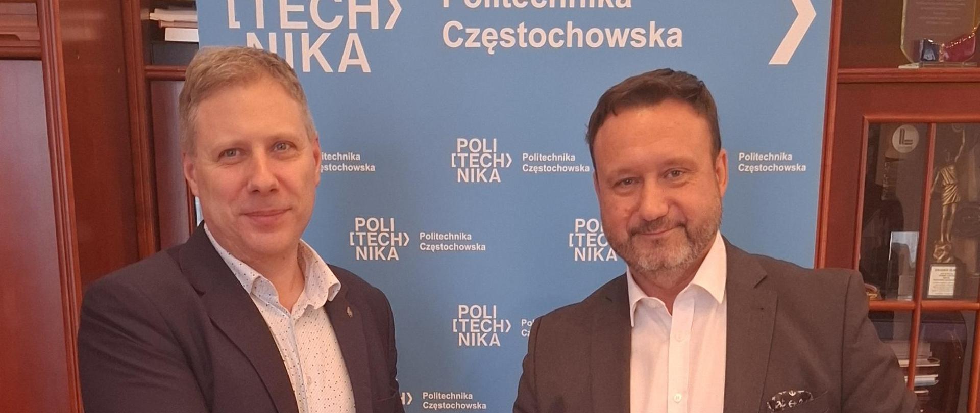 Od lewej: prof. Marek Warzecha, dyrektor generalny Jarosław Fiks. Panowie stoją trzymając teczki w dłoniach oraz podając sobie prawe ręce. 