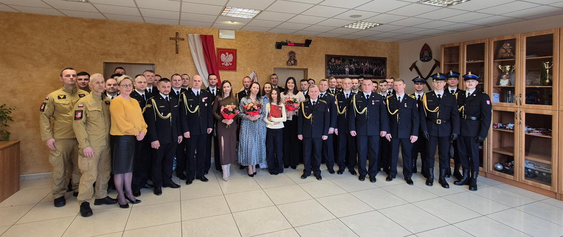 Duże zdjęcie grupowe wszystkich uczestników uroczystości: strażaków w różnych typach umundurowania oraz zaproszonych kobiet.