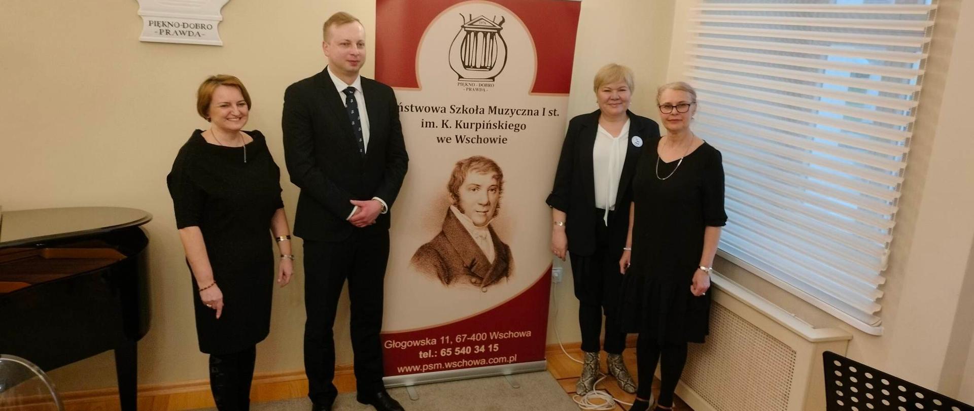 Przedstawiciele Szkół Muzycznych z Nowego Tomyśla, Wolsztyna, Zbąszynia oraz Wschowy - wspólne zdjęcie na tle baneru z logotypem szkoły we Wschowie