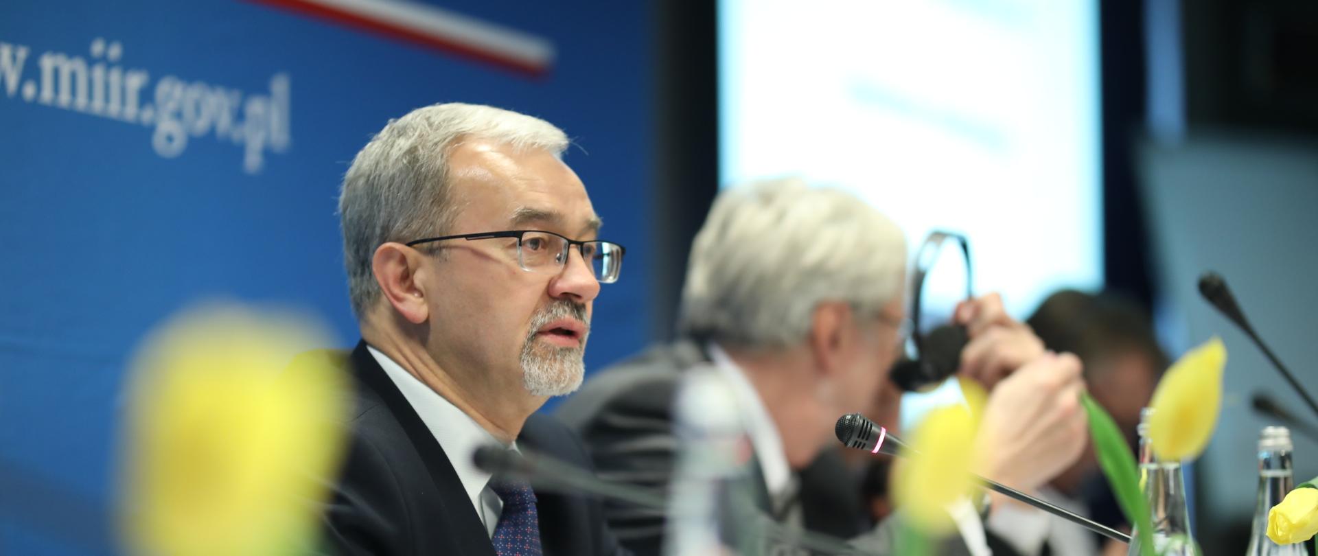 Minister Jerzy Kwieciński przy stole prezydialnym podczas rozpoczęcia rozmów z przedstawicielami Komisji Europejskiej.