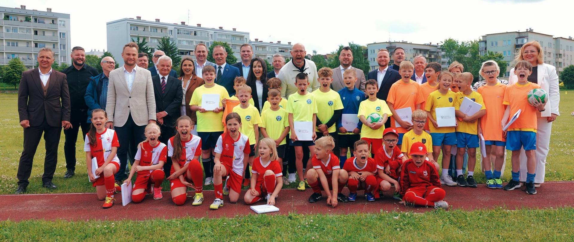 Zbiorowe zdjęcie młodych zawodników i przedstawicieli lokalnych władz z ministrem sportu i turystyki Jakubem Rutnickim.