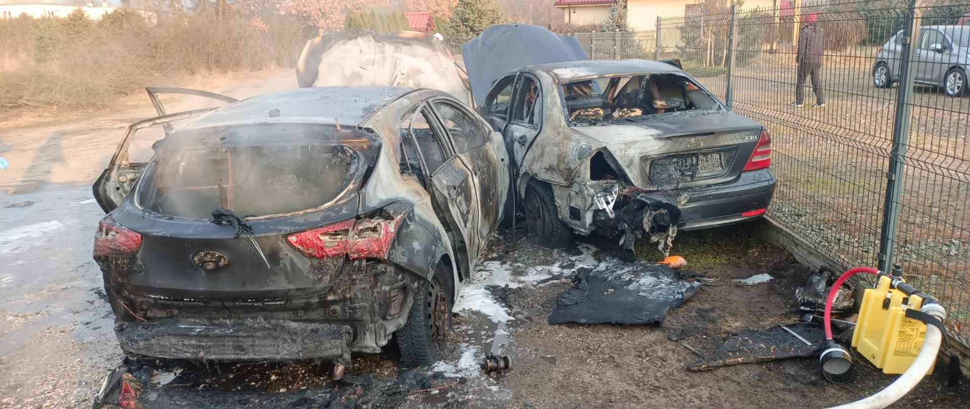 Dwa spalone samochody na poboczu drogi