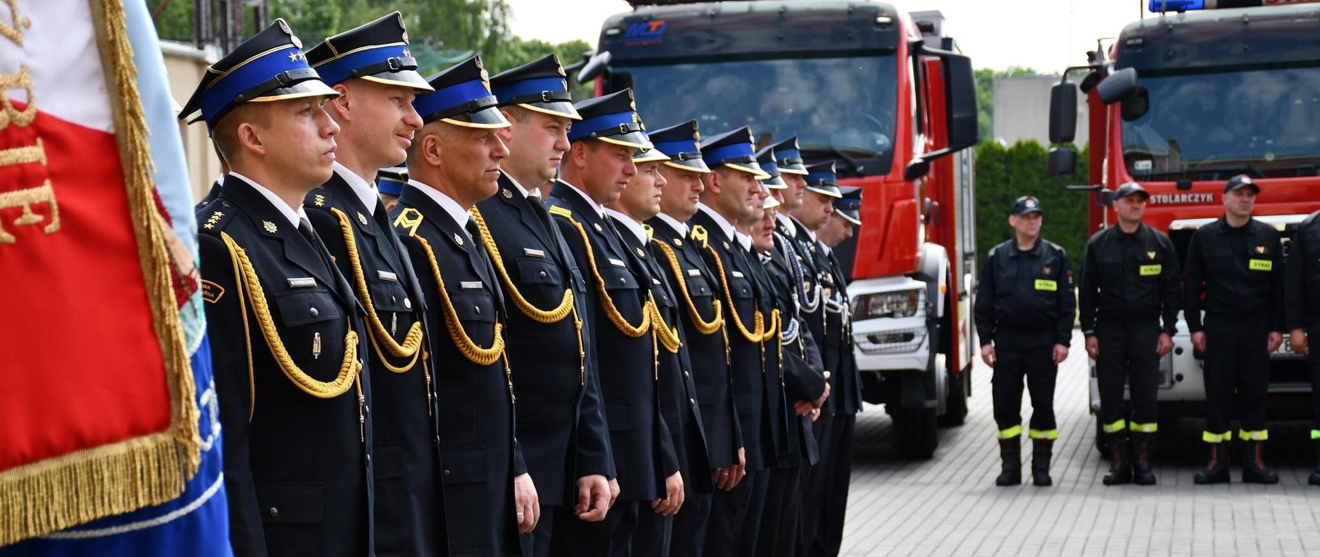 Zdjęcie przedstawia strażaków PSP i OSP na tle pojazdów pożarniczych