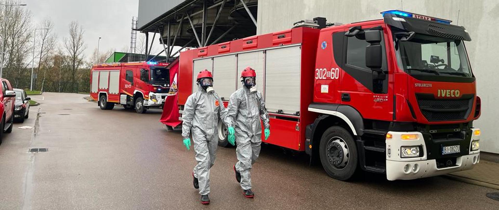 Strażacy na tle samochodów pożarniczych