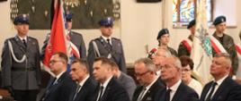Minister Czarnek w otoczeniu uczestników pogrzebu siedzi w ławie.
