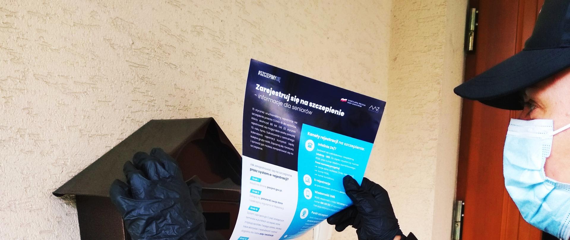 Na zdjęciu widoczny strażak OSP wkładający ulotkę o szczepieniach do skrzynki na listy.