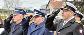 Przedstawiciele służb mundurowych stoją obok siebie oddając honor.