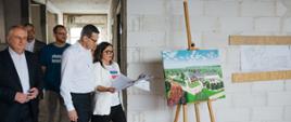 Prezes hospicjum oraz premier idą po budowie hospicjum.