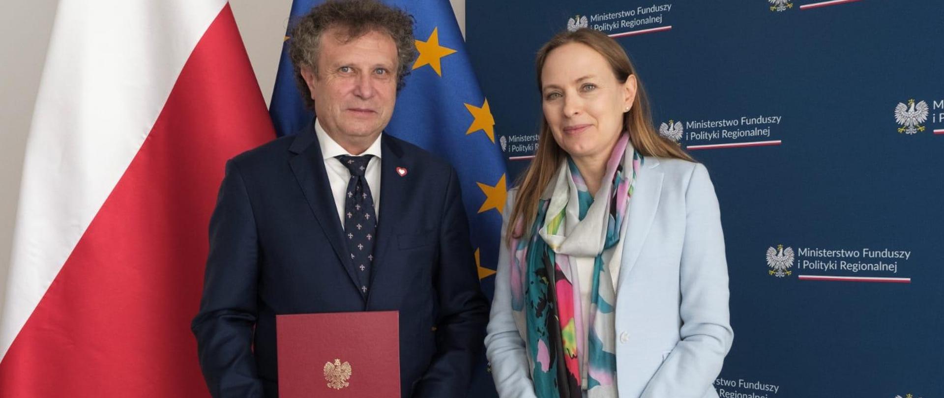 Dwie osoby stoją obok siebie. Pierwszy od lewej stoi wiceminister Jacek Karnowski. 