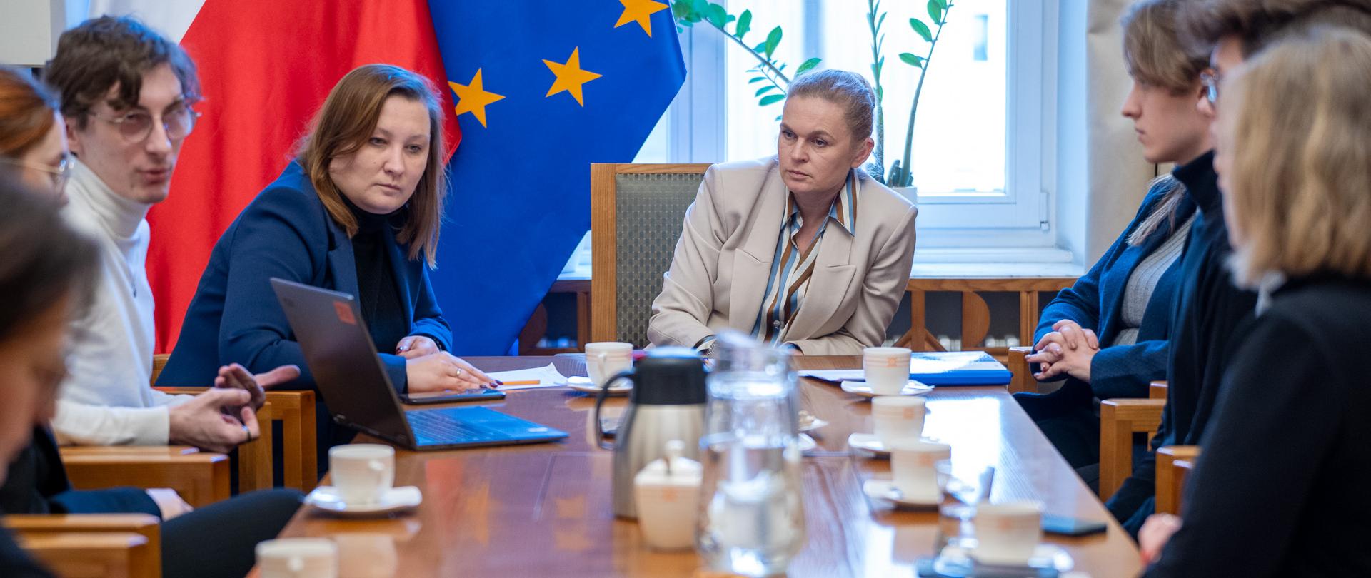 Na zdjęciu ministra Barbara Nowacka, wpatrzona w laptop, po lewej stronie ministra Piechna-Więckiewicz. Obydwie Panie analizują wyniki raportu przedstawianego na laptopie przez przedstawiciela fundacji