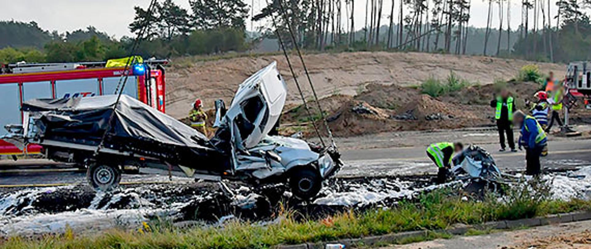 Zdjęcie przedstawia wrak samochodu podnoszonego przez dźwig