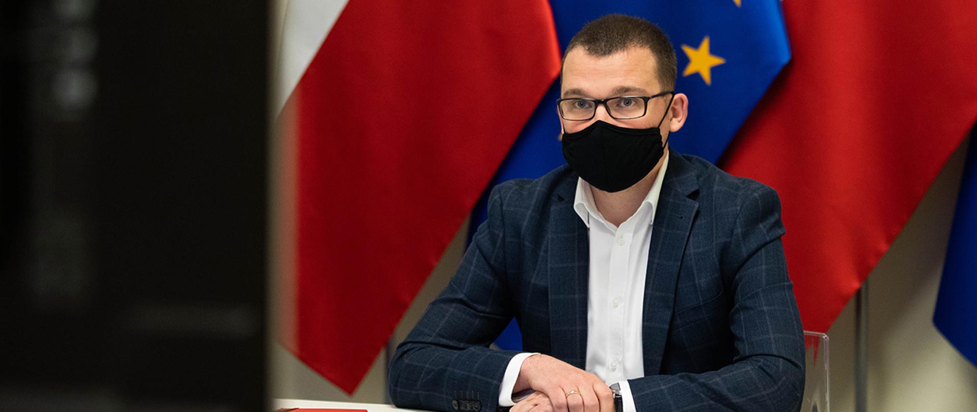 Wiceminister Paweł Szefernaker przed ekranem podczas wideokonferencji z premierem Mateuszem Morawieckim oraz przedstawicielami KWRiST.