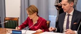 Od lewej siedzą minister rozwoju i wiceprezes UOKiK. Podpisują porozumienie.