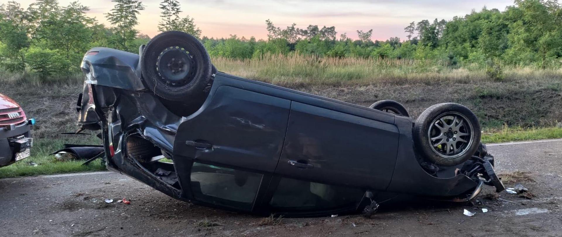 Samochód osobowy po dachowaniu na środku drogi