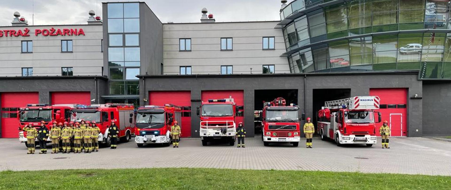 Samochody przed garażami JRG nr 1 w Nowym Sączu a obok strażacy.