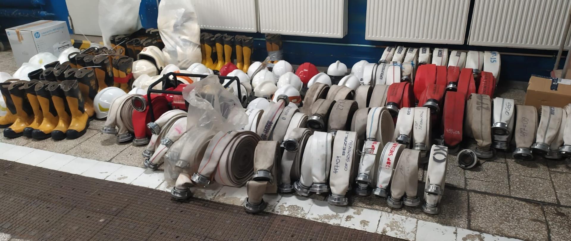 Na zdjęciu znajduje się sprzęt pożarniczy, tj. węże, buty bojowe, agregat prądotwórczy