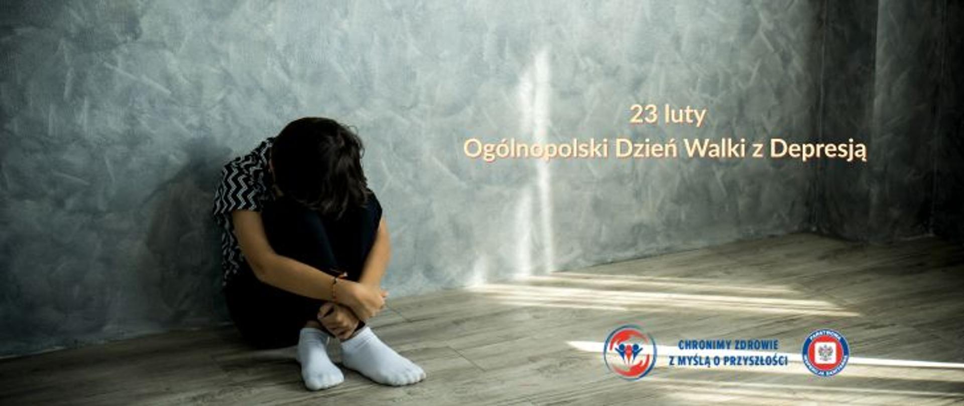 W pokoju na podłodze siedzi smutna skulona osoba w ciemny stroju. Po prawej stronie jasny napis 23 luty. Ogólnopolski Dzień Walki z Depresją. W prawym dolnym rogu logo Państwowej Inspekcji Sanitarnej wraz z hasłem chronimy zdrowie z myślą o przyszłości. Ściany w kolorystyce szarej. 
