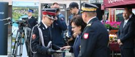 Pani marszałek wraz z zastępca komendanta głównego PSP wręczają kluczyki i dowód rejestracyjny strażakowi