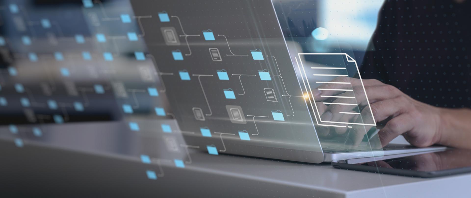 Na pierwszym planie laptop a na drugim męskie dłonie dotykające dotykające klawiatury.