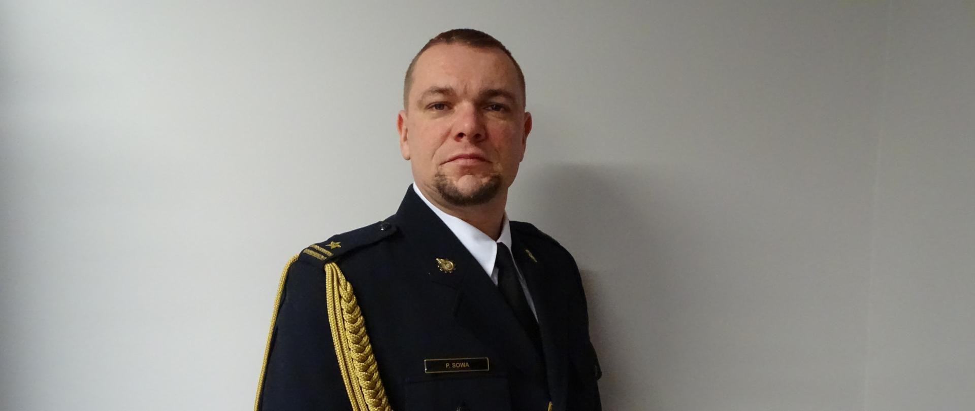 Zdjęcie portretowe zastępcy komendanta mł. bryg. Pawła Sowy na jasnym tle w mundurze galowym.