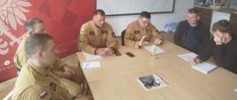 Przedstawiciele jednostek OSP oraz przedstawiciele samorządów gminnych podczas spotkania z kierownictwem Komendy Powiatowej PSP w Lwówku Śląskim siedzący wspólnie przy stole.