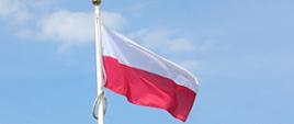 Fotografia przedstawia zbliżenie na łopoczącą na wietrze biało-czerwoną flagę państwową