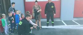 Zdjęcie przedstawia dzieci podające prąd wody pod nadzorem funkcjonariuszy PSP.