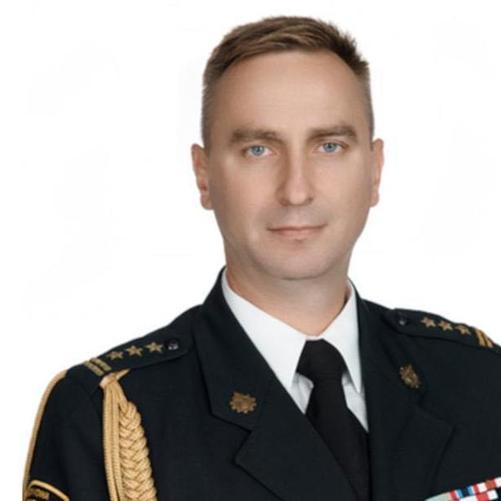 Zdjęcie portretowe komendanta powiatowego st. bryg. mgr inż. poż. Tomasza Szymańskiego w mundurze galowym na jasnym tle 