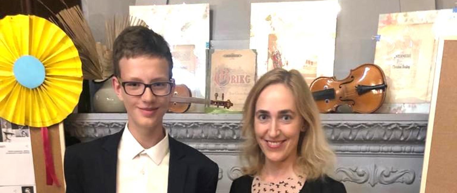 Zdjęcie przedstawiające Pawła Taraszkiewicza, laureata konkursu w Słupsku, stojącego z dyplomem. Obok ucznia stoi nauczyciel - Marta Ożelska-Kurzawa.