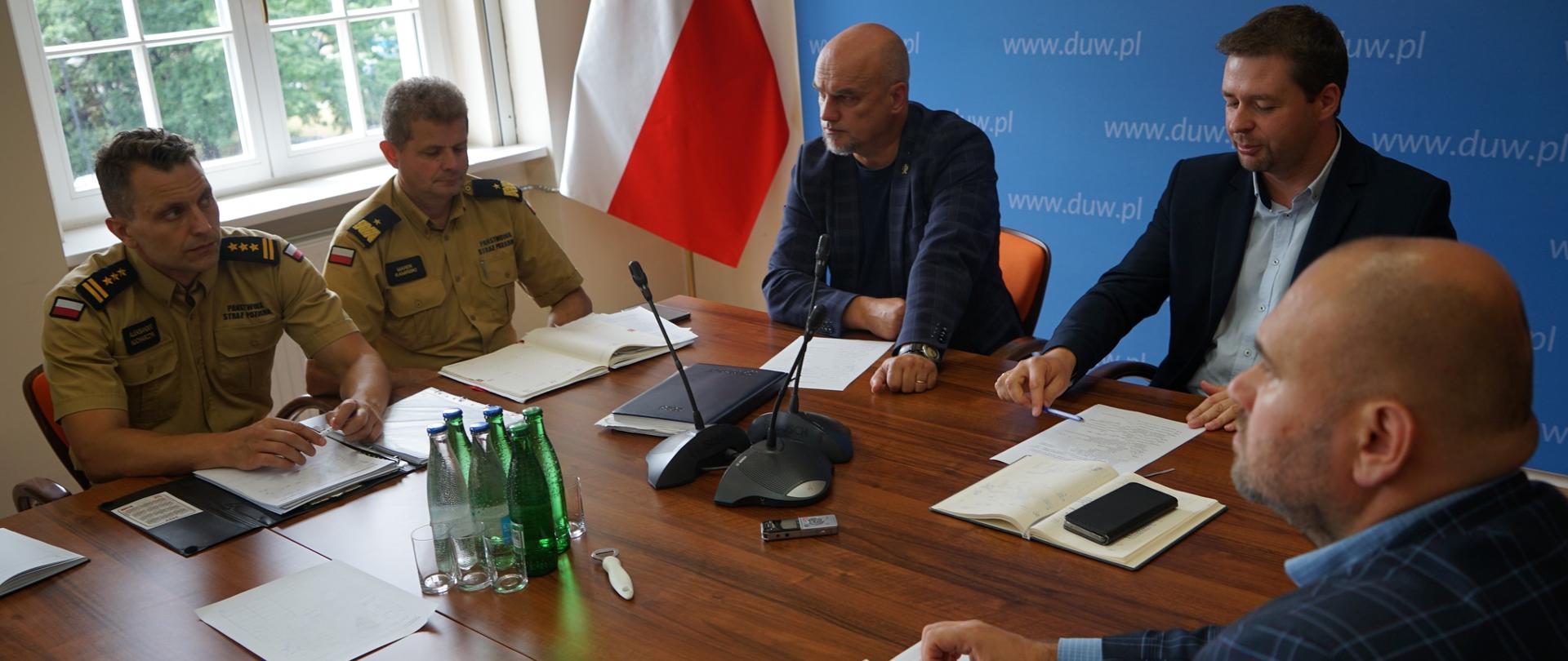 Pięć osób siedzących przy stole na spotkaniu.