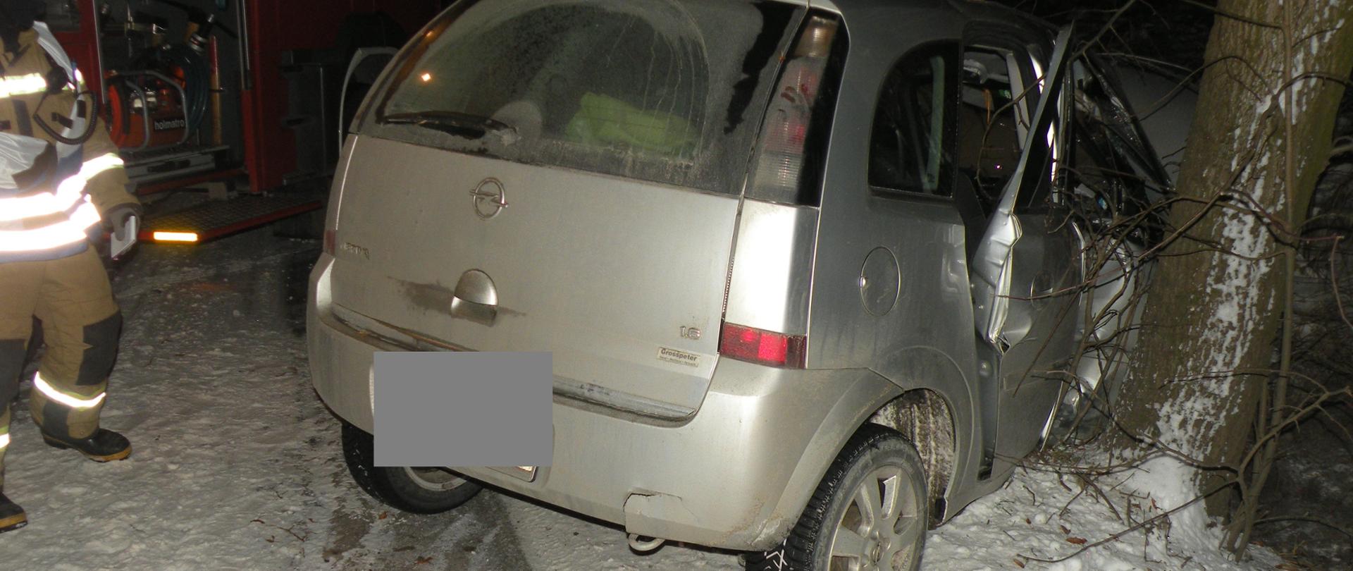 Srebrny samochód marki opel meriva uderzyl w drzewo, stoi w rowie, strazak PSP
