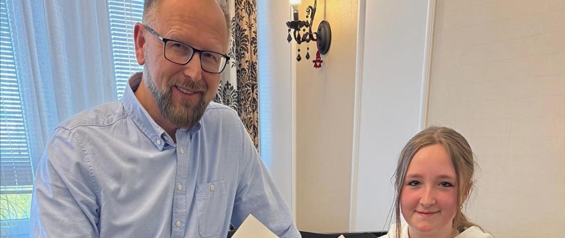 Janusz Ostrowski, Laura Pietryka. Nauczyciel i uczennica trzymają dyplomy, w tle fortepian