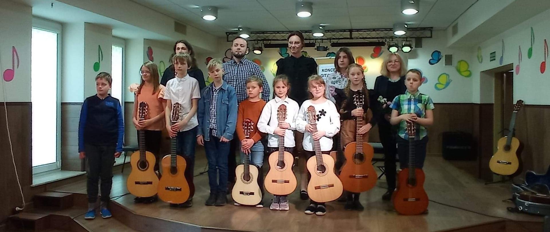 Warsztaty gitarowe w szkole muzycznej na zdjęciu uczniowie i nauczyciele