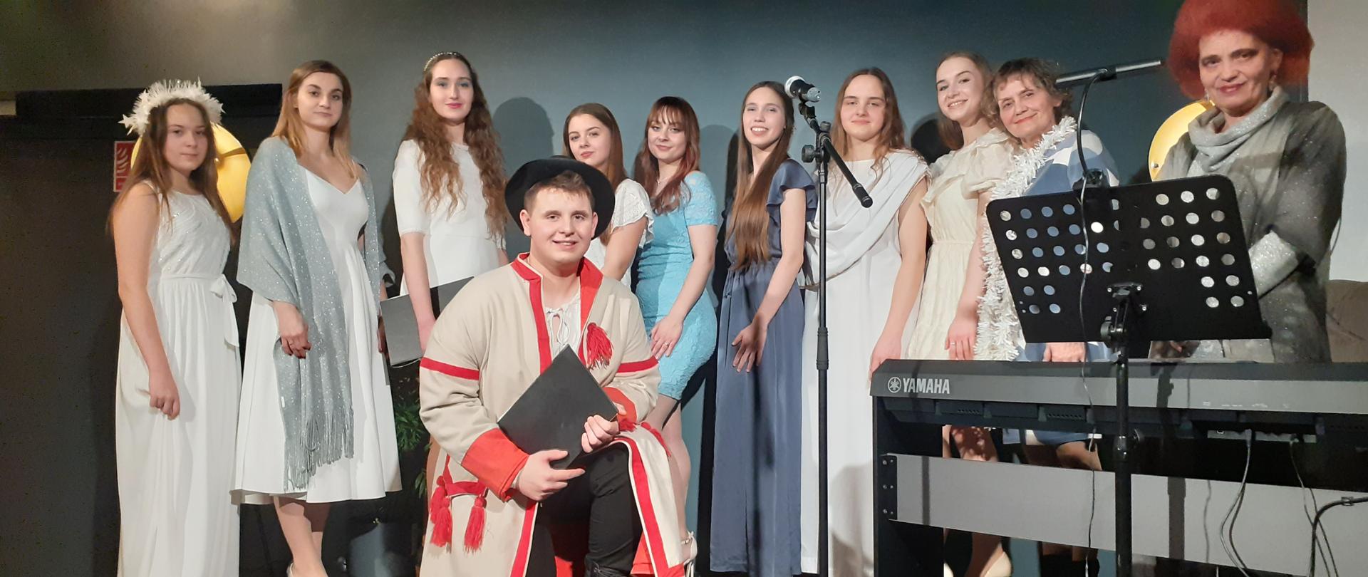 Na scenie stoją słuchacze studium wraz z nauczycielką przy keyboardzie. 