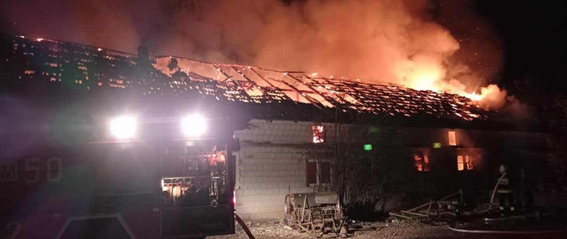 strażacy prowadzą działania gaśnicze na obiekcie objętym pożarem - widać ruiny więźby dachowej, łunę ognia i wydobywający się dym