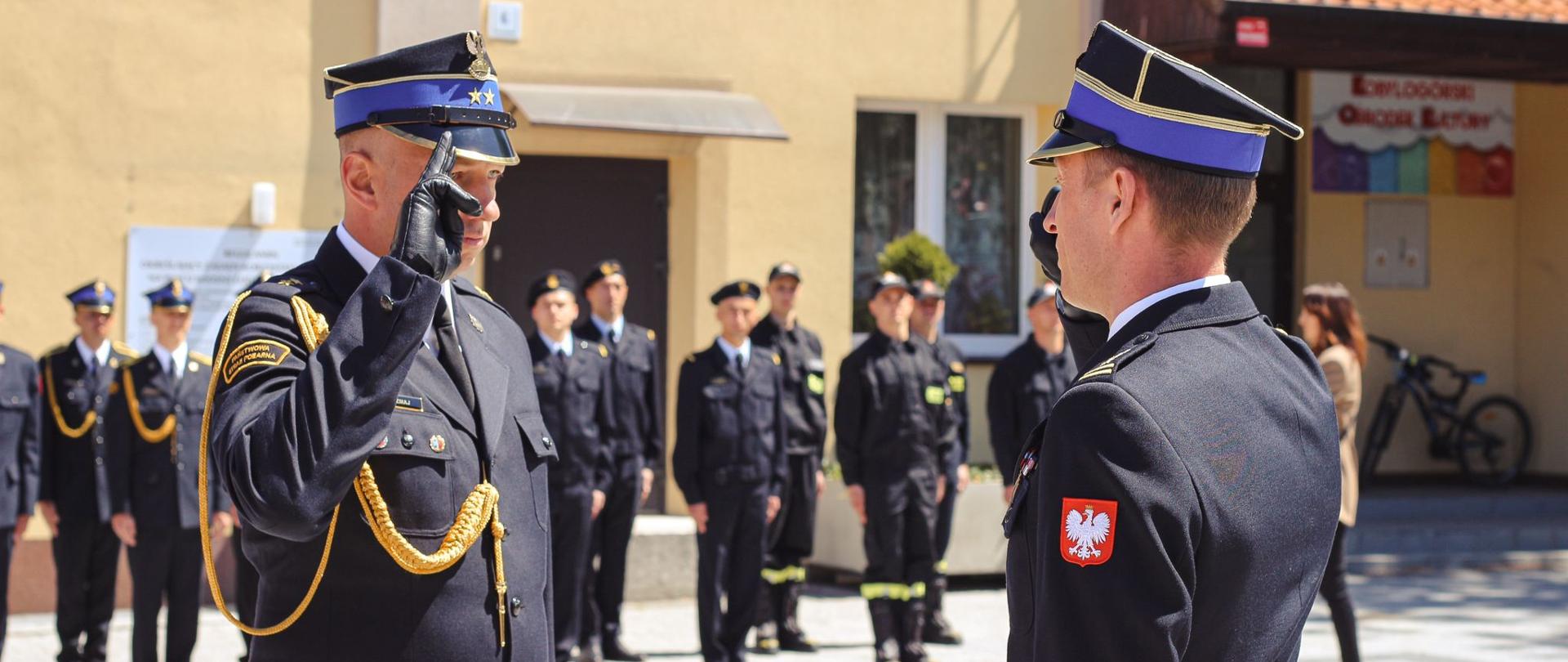 Dowódca uroczystości złożył meldunek Zastępcy Komendanta Wojewódzkiego PSP w Poznaniu. Na drugim planie pododdział strażaków biorący udział w uroczystości.
