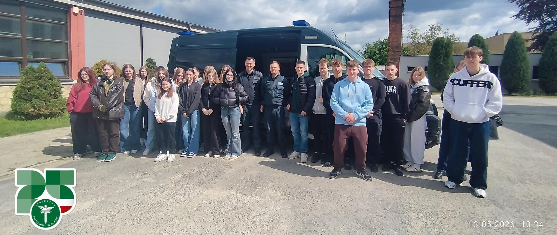 Grupowe zdjęcie uczniów i inspektorów WITD Opole przed specjalistycznym pojazdem inspekcyjnym na terenie szkoły w Strzelcach Opolskich.