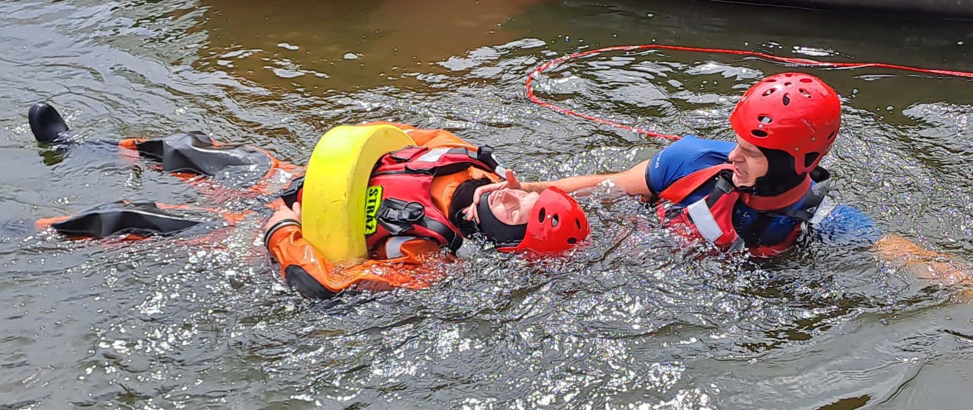 Zdjęcie przedstawia strażaków podczas ćwiczeń doskonalących wodnych.
W tle akwen wodny - jezioro.
