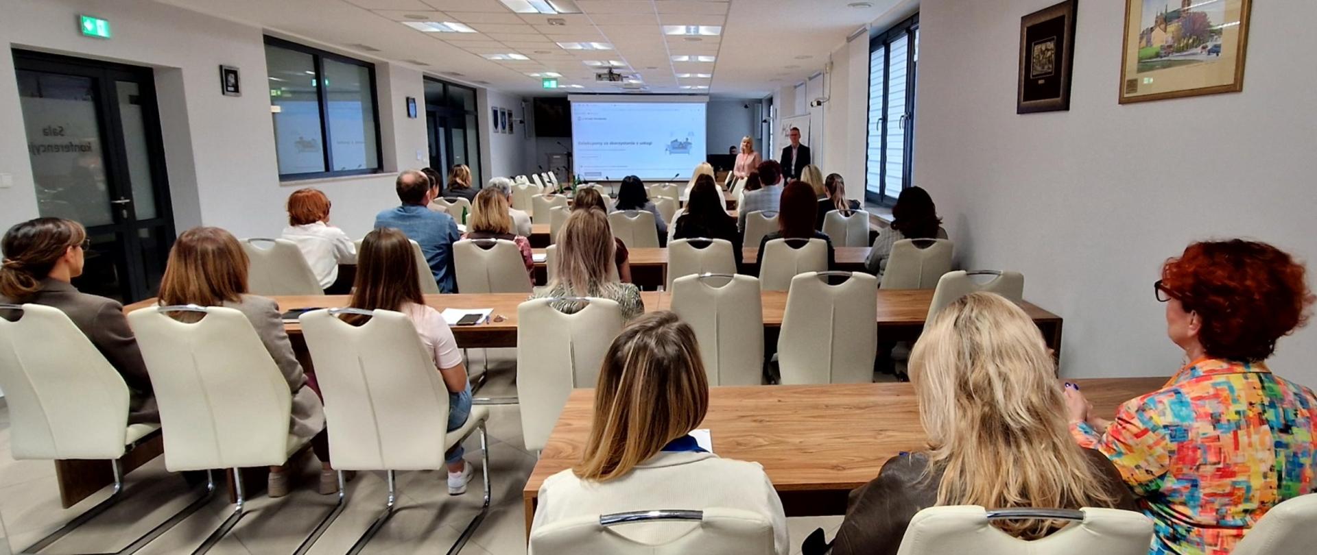 W sali siedzi grupa osób i słucha wykładu o podatkach